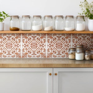 May include: A kitchen backsplash with brown and white patterned tile. The tile has a floral design. There are glass jars on a wooden shelf above the tile.