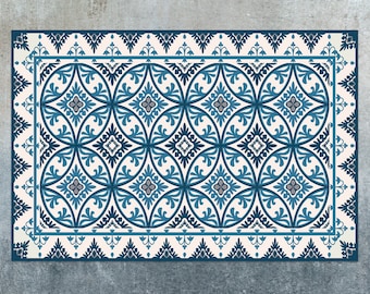 May include: A white and blue patterned rug with a geometric design. The rug has a border of blue and white floral motifs.