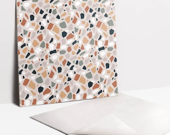 May include: A square adhesive tile featuring a repeating terrazzo pattern with irregular fragments in shades of terracotta, sage green, charcoal gray, and white set against a light beige background, with a partially peeled backing layer.