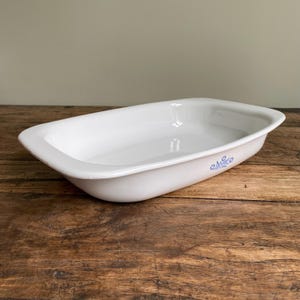 May include: White rectangular baking dish with a blue floral design. The dish is made of ceramic and has a glossy finish.