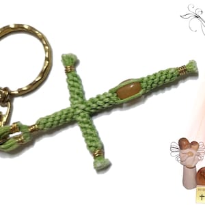 May include: Green knotted rope cross keychain with a gold ring and clasp. The cross has a light brown stone bead in the centre.