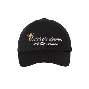 Puede incluir: Gorra de béisbol negra con una corona dorada y el texto "Ditch the clowns, get the crown" bordado en blanco.
