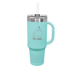 May include: A turquoise stainless steel travel mug with a handle and a straw. The mug has a black lid and a silver logo that says "STANLEY".