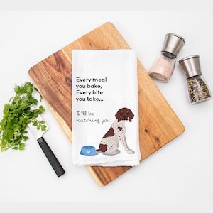 May include: White kitchen towel with a brown and white dog illustration and the text "Every meal you bake, Every bite you take... I'll be watching you."