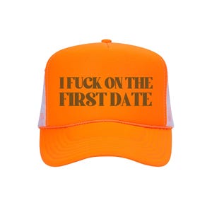 Może przedstawiać: Jasnopomarańczowa czapka typu trucker z białym tyłem z siatki. Na czapce znajduje się napis "I FUCK ON THE FIRST DATE" w ciemnobrązowych, blokowych literach. Tło jest białe.