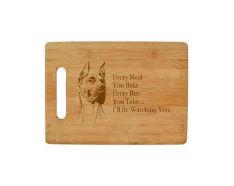 Könnte beinhalten: Ein braunes Bambus-Schneidebrett mit einem lasergravierten Bild eines Doggenhundes und dem Text "Every Meal You Bake Every Bite You Take... I'll Be Watching You."