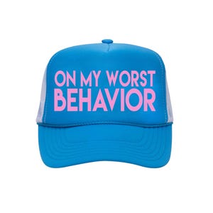 Può includere: Cappellino da camionista blu con la scritta rosa "ON MY WORST BEHAVIOR". Il cappello ha una visiera curva e un retro in rete bianca. Un accessorio casual.