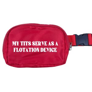 Puede incluir: Una riñonera roja con hebilla y correa negras. La riñonera tiene cierre de cremallera y el texto "MY TITS SERVE AS A FLOTATION DEVICE" en blanco.