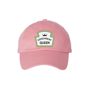 May include: Pink baseball cap with a green and white label that says "Condiment Queen" with a crown above the word "Condiment".