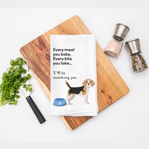 May include: White kitchen towel with a beagle dog illustration and the text "Every meal you bake, Every bite you take... I'll be watching you."