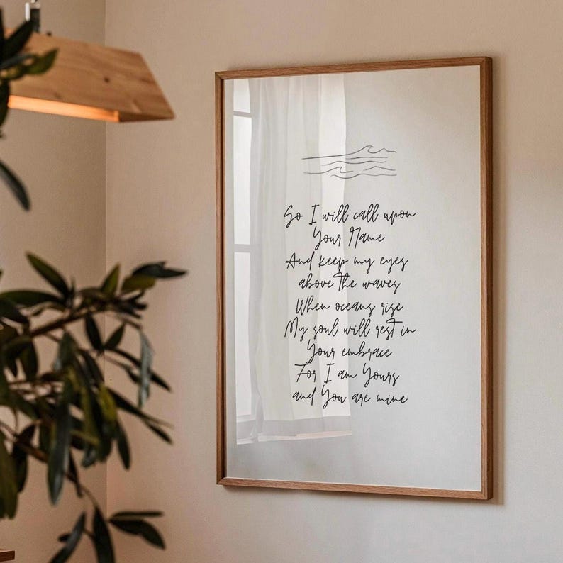 Op de afbeelding: Een ingelijst print met een handgeschreven gedicht over liefde en toewijding. Het gedicht luidt: "So I will call upon Your Name And keep my eyes above The waves When oceans rise My soul will rest in Your embrace For I am Yours and You are mine"