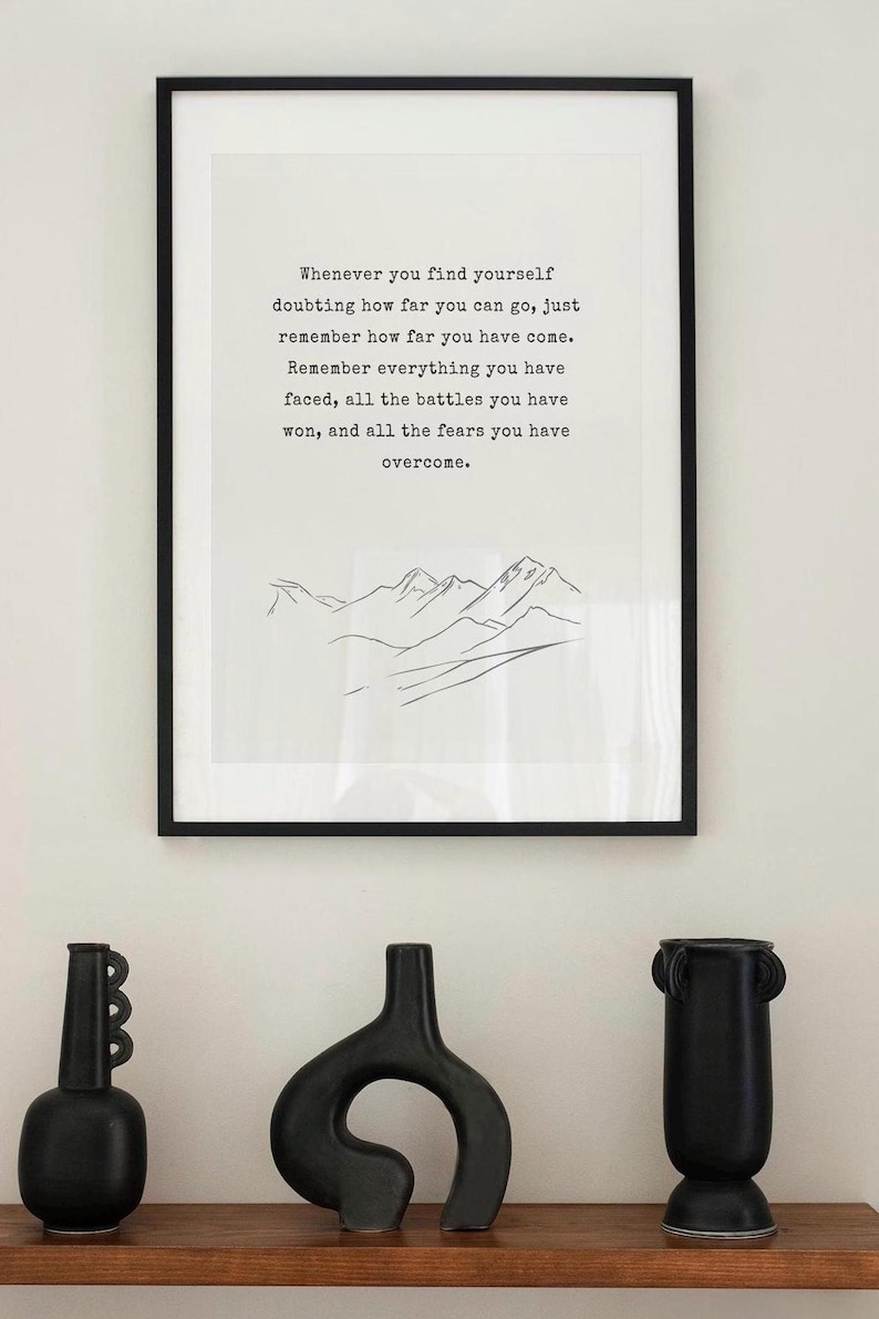 May include: A black and white inspirational quote print with a simple line drawing of mountains. The quote reads "Whenever you find yourself doubting how far you can go, just remember how far you have come. Remember everything you have faced, all the battles you have won, and all the fears you have overcome."