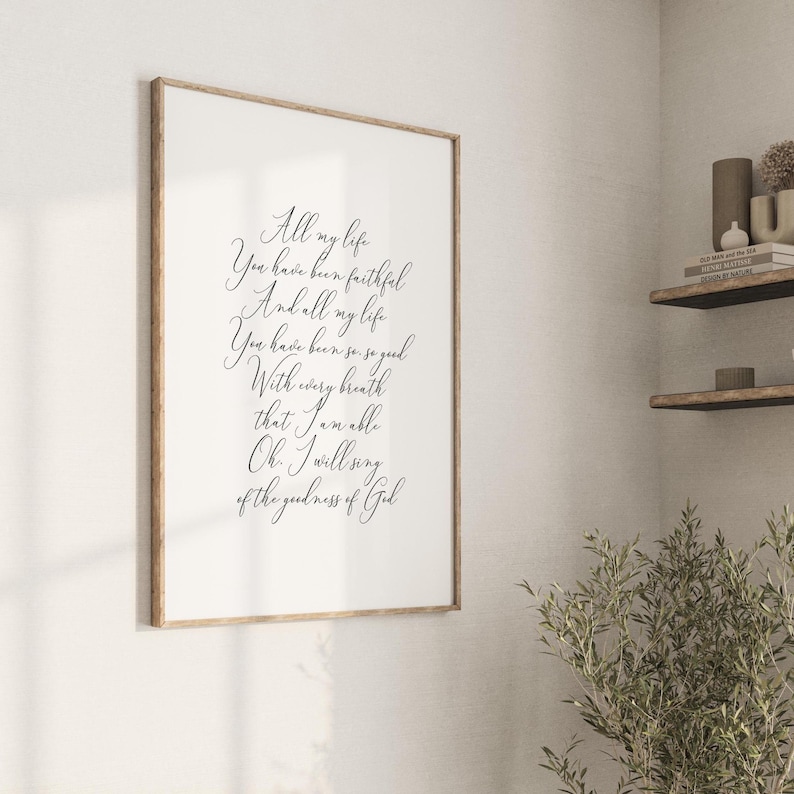 Op de afbeelding: Een ingelijst afdruk met een witte achtergrond en zwarte kalligrafietekst. De tekst luidt "Heel mijn leven Ben je trouw geweest En heel mijn leven Ben je zo goed geweest Met elke ademhaling die ik doe, ben ik in staat Oh, ik zal zingen van de goedheid van God."
