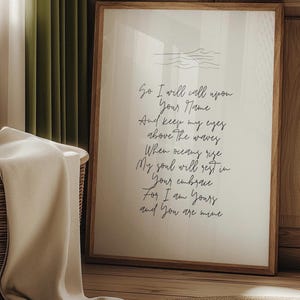 May include: A white framed print with a handwritten poem about love and the ocean. The poem reads: "So I will call upon Your Name And keep my eyes above the waves When oceans rise My soul will rest in Your embrace For I am Yours and You are mine"