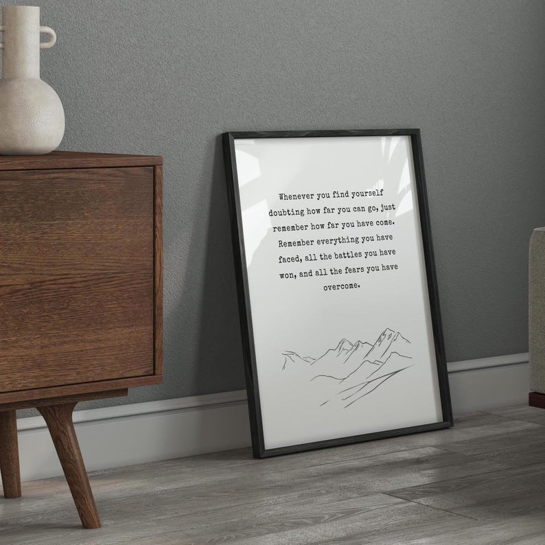 May include: Black and white motivational quote print with a simple line drawing of mountains. The quote reads: "Whenever you find yourself doubting how far you can go, just remember how far you have come. Remember everything you have faced, all the battles you have won, and all the fears you have overcome."