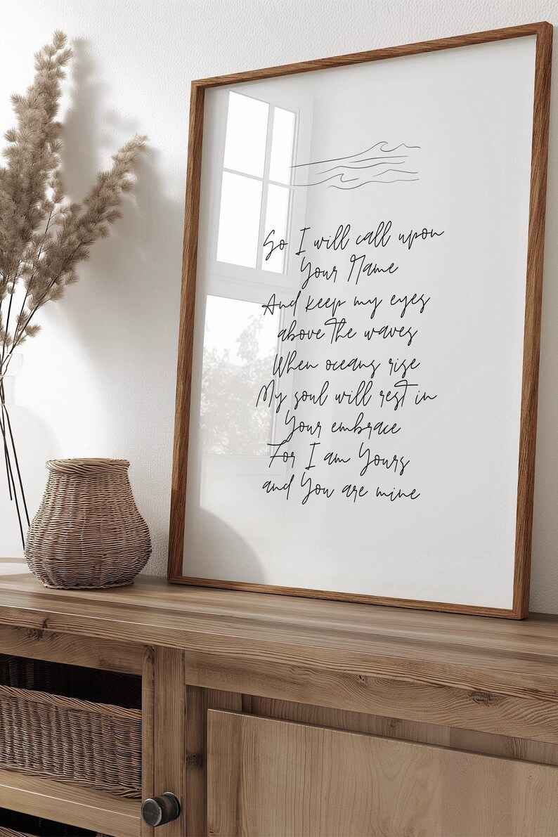 Op de afbeelding: Een ingelijst afdruk met een witte achtergrond en zwarte tekst. De tekst luidt "So I will call upon Your Name And keep my eyes above The waves When oceans rise My soul will rest in Your embrace For I am Yours and You are mine".