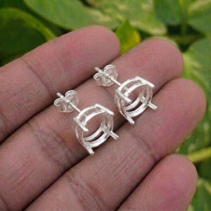 Puede incluir: Un par de monturas para pendientes de botón en plata con un soporte circular de garras diseñado para sujetar una piedra preciosa. Cada pendiente incluye un poste y un cierre de mariposa, con un acabado metálico pulido y estructura.