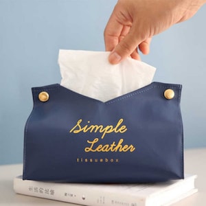 May include: A blue leather tissue box cover with gold accents and the text "Simple Leather tissuebox" in gold lettering.