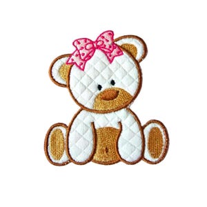 Puede incluir: Oso de peluche blanco con un lazo rosa, sentado con las piernas cruzadas. El oso tiene ojos y nariz bordados en marrón.