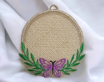 May include: A round, beige, embroidered coaster with a green leafy border and a purple butterfly in the center.
