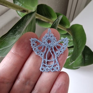 May include: A delicate blue lace angel ornament, perfect for adding a touch of elegance to your holiday decor.