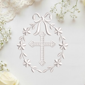 Könnte beinhalten: Weißes Stickdesign mit einem Kreuz in der Mitte, umgeben von einem Blumenkranz und einer Schleife oben. Das Design befindet sich auf einem weißen Hintergrund mit zarten Blumen und Spitze in den Ecken.