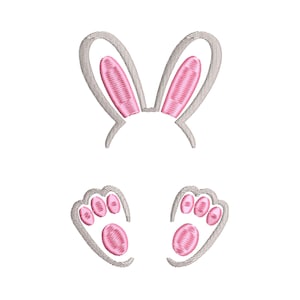 Puede incluir: Orejas y patas de conejo bordadas en rosa y gris. Las orejas son grandes y caídas, mientras que las patas tienen tres dedos cada una.