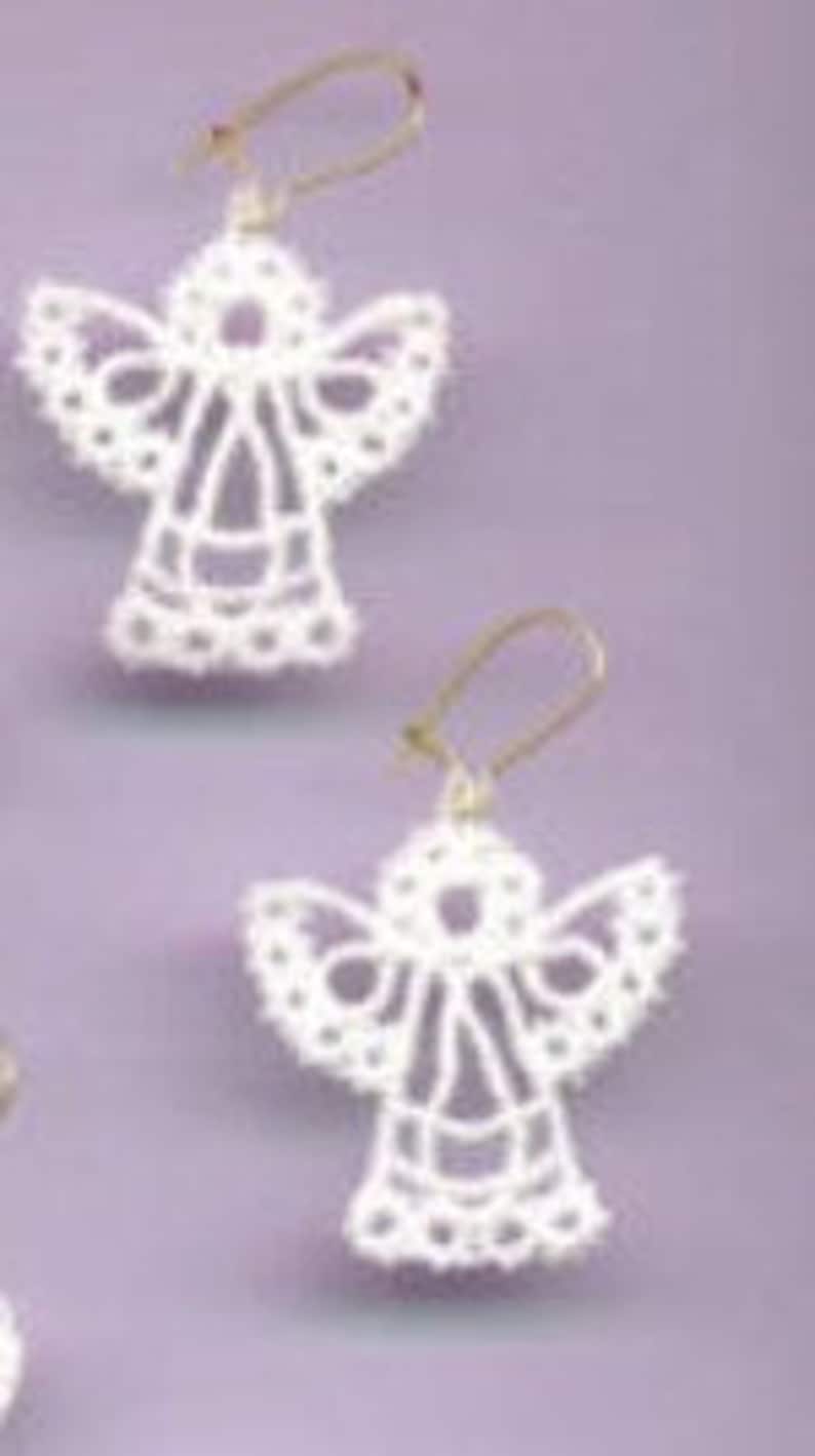 May include: A pair of white lace angel earrings with gold hooks.