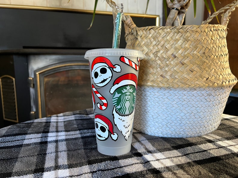 Pu&ograve; includere: Una tazza riutilizzabile bianca con un design a tema natalizio che presenta il personaggio Jack Skellington del film "Nightmare Before Christmas". Il design include anche bastoncini di zucchero, cappelli di Babbo Natale e un logo Starbucks.