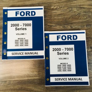 May include: Two blue and white Ford 2000-7000 Series service manuals. The manuals are labeled Volume 1 and Volume 2. The manuals list the models covered: 2000, 3000, 4000, 5000, 5100, 5200, 7000, 3400, 3500, 4400, 4500, and 5500.