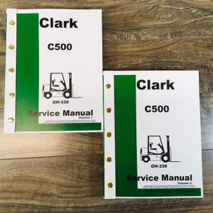 May include: Two green and white service manuals for a Clark C500 forklift. The manuals are labeled "Volume 1" and "Volume 2".
