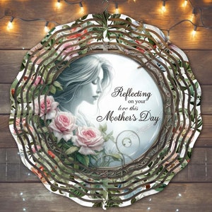 May include: A round, multi-layered metal wind spinner with a floral design. The center features a woman's face and roses. The text "Reflecting on your love this Mother's Day" is printed on the spinner.