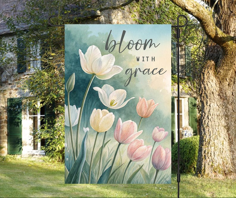 May include: A garden flag with a watercolor design of white and pink tulips. The text "bloom with grace" is written in a script font on the flag.