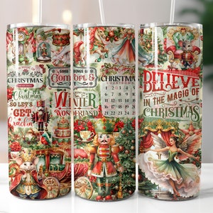 May include: Three stainless steel tumblers with Christmas-themed designs. Each tumbler features a different festive illustration, including a nutcracker, a ballerina, and holiday text. The designs incorporate red, green, and gold colors, with text that reads "Believe in the Magic of Christmas."