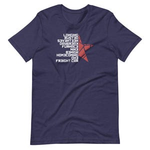 May include: Navy blue t-shirt with white text and a red star graphic. The text includes the words "Longing", "Rusted", "Seventeen", "Daybreak", "Furnace", "Nine", "Benign", "Homecoming", "One", and "Freight Car".