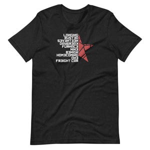 May include: Dark gray t-shirt featuring a red star design with white text. The text includes words like "Longing", "Rusted", and "Freight Car". The shirt is a short-sleeved crew neck.