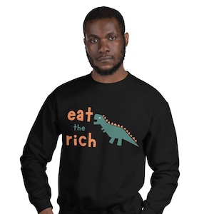 May include: Black sweatshirt with the text "eat the rich" in orange and a green dinosaur graphic.