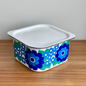 Puede incluir: Una taza de cerámica blanca con un asa negra y el texto "But First, Coffee" en negro, con una fuente de estilo manuscrito. La taza está sobre una superficie blanca.