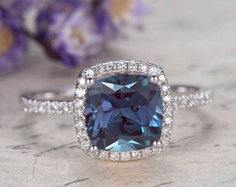 Könnte beinhalten: Ein quadratischer blauer Edelsteinring mit einem Heiligenschein aus kleineren Diamanten. Der Ring ist in Weißgold gefasst.