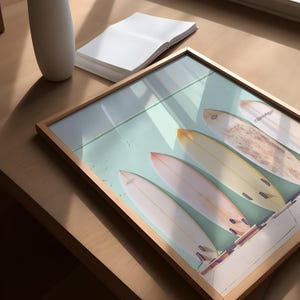 May include: A framed print of five vintage surfboards displayed against a light teal background. The surfboards are various pastel shades of yellow, orange, and pink. The frame is light wood.  The image is a beach-themed wall art piece.