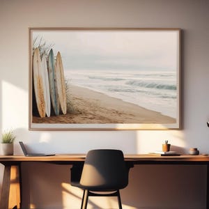 May include: A framed print featuring a beach scene with surfboards. The artwork depicts several weathered surfboards leaning against beach grass on a sandy shore. The ocean waves and sky are visible in the background, creating a coastal theme.