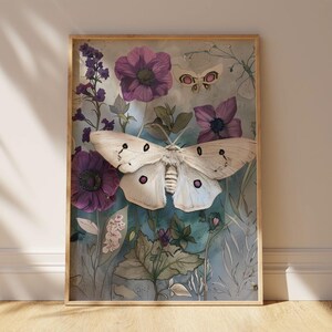 May include: A framed print featuring a white moth with purple accents, surrounded by purple flowers and green foliage on a blue background.