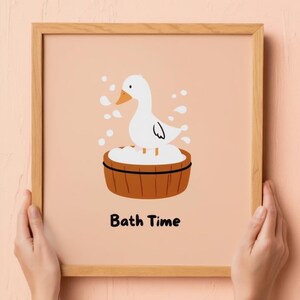May include: A framed print featuring a cartoon duck in a wooden tub filled with bubbles. The duck is white with an orange beak and is surrounded by water droplets. The words "Bath Time" are printed in black below the image.