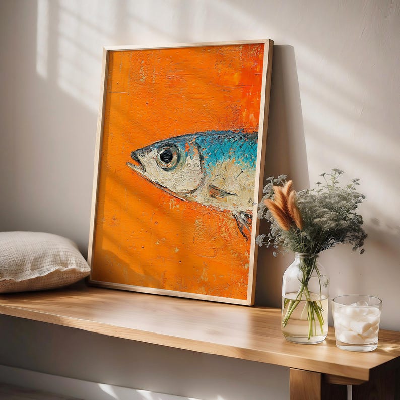 May include: A framed painting of a blue and white fish on an orange background. The fish is facing to the right and has a large eye. The painting is in a wooden frame.