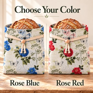 May include: Two fabric bread bags with a floral and butterfly print, each containing a loaf of bread. The left bag features blue roses, and the right bag features red roses. Both bags have a beige ribbon closure with a wooden bead. Text reads: Choose Your Color, Rose Blue, Rose Red.