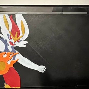 May include: A black Nintendo Switch console with a custom design featuring a white and red Pokemon character with flames. The character is on the left side of the console, and the right side of the console has red Joy-Cons.