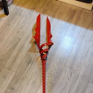 May include: A red, twisted, metal spear with a pointed tip and two curved blades at the top.