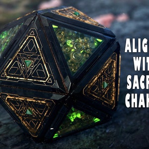 May include: A black and gold geometric crystal with green accents. The crystal is inscribed with the text "ALIGNED WITH SACRAL CHAKRA".