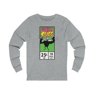 Op de afbeelding: Een grijs longsleeve t-shirt met een grafische print van een groene gorilla-bug met de tekst "GORILLA BUGS" in roze en gele letters. De afbeelding bevat ook de tekst "25c 16 JUL 3991".