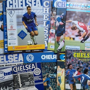 May include: A collection of vintage Chelsea Football Club matchday programmes. The programmes feature the team's logo, the date of the match, and the opponent. The programmes are in various colours, including blue, red, and white.